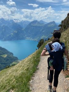 Photo of Lidia hiking in Swiss mountains with a baby in the back carrier
